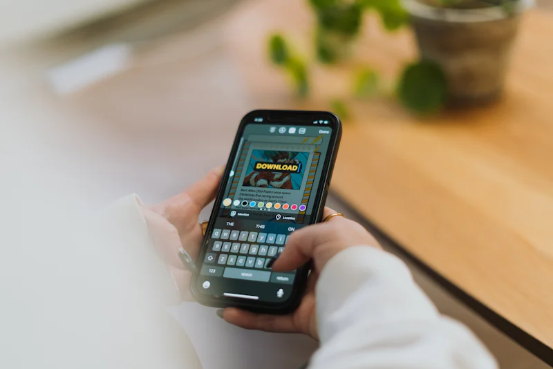 Person holding a smartphone showing a download button on screen