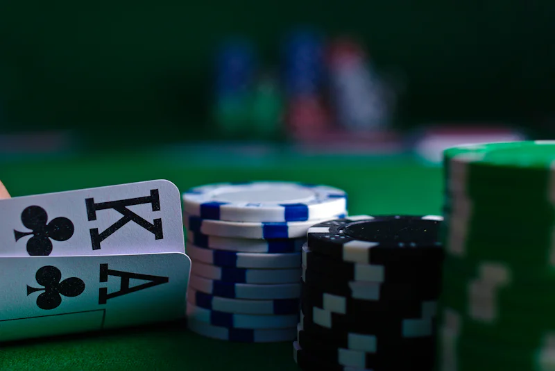 King and ace of clubs beside stacks of poker chips on green felt